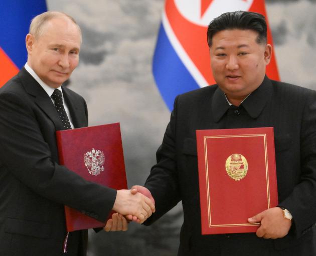 Russia's President Vladimir Putin shakes hands with North Korea's leader Kim Jong Un at a signing...