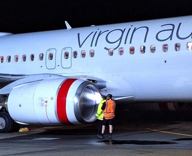 An aircraft engineer inspects the damaged engine of the Virgin Australia Boeing 737-8FE. PHOTO:...