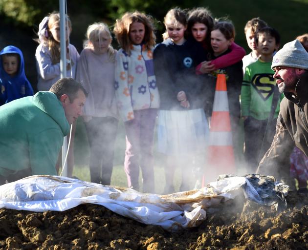 Balaclava School teacher and parent Shane Parker (left) and parent Paul Kepa pull the hāngī out...