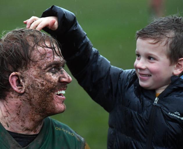 Ollie McLennan, 6, gives mud-splattered Green Island forward Amos Roddick a pat on the head after...