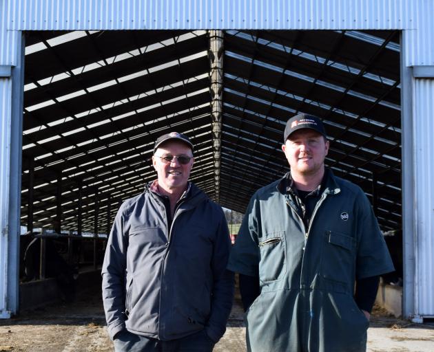 Richard Peirce and his son Alex stand outside the freestall barn on their family farm Riverside,...