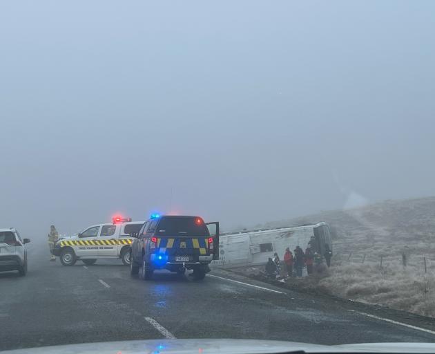 Passengers huddle outside one of the buses following the two crashes near Lake Pukaki. Photo:...