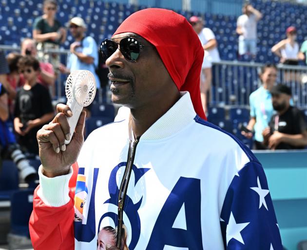 American US rapper Snoop Dogg holds a hand-held fan at Eiffel Tower Stadium in Paris. REUTERS