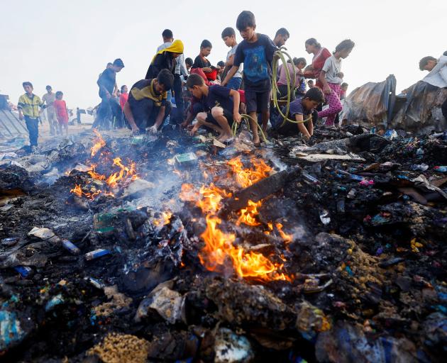 Palestinians search for food among burnt debris in the aftermath of an Israeli strike on an area...