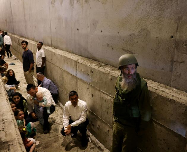 People take shelter during an air raid siren after Iran fired a salvo of ballistic missiles, in...