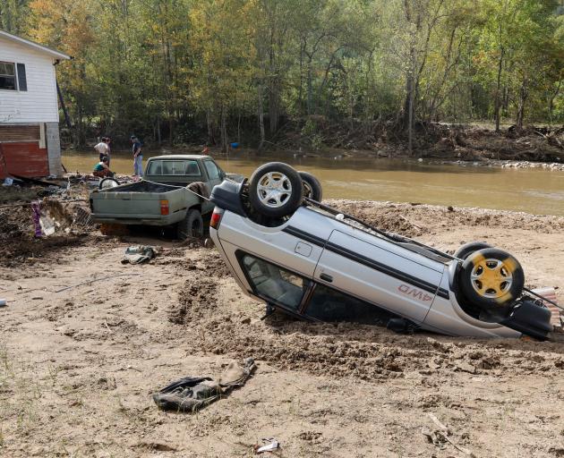 An upside-down car lies in mud on the banks of a creek in the aftermath of Hurricane Helene, in...
