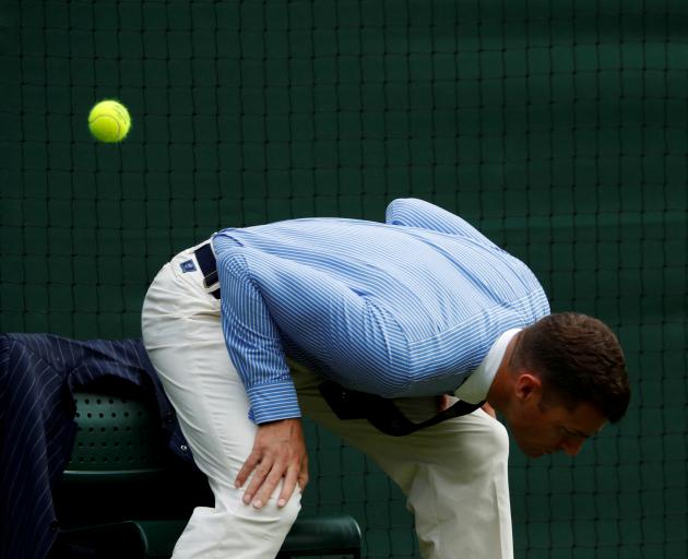 A Wimbledon line judge dodges a tennis ball. Photo: Reuters
