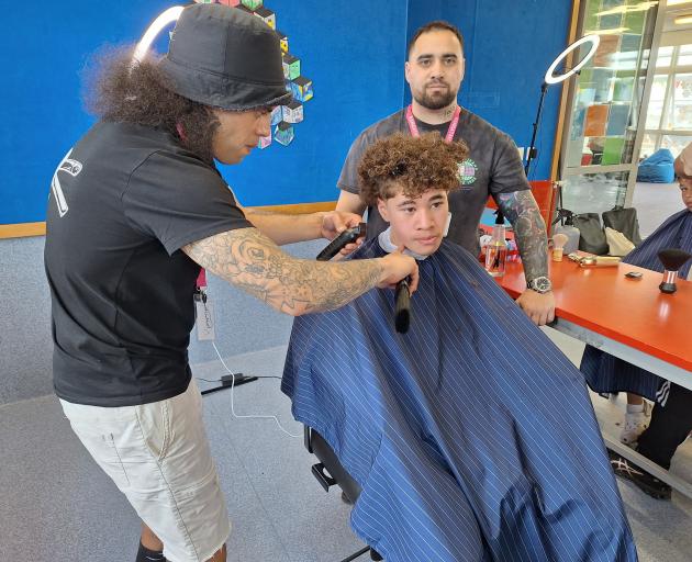 OnlyFades Barbershop owner Toma Waihirere (back) watches on as barber Vinnie Nahv gives Kobe Ryan...