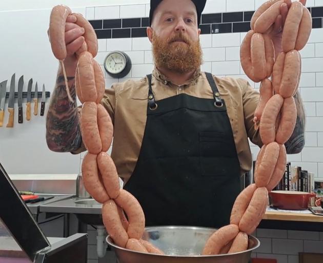 Greg Egerton, of Links Quality Meats, hoists two strings of the butchery’s award-winning sausages...