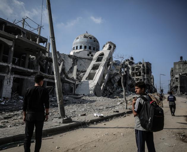 Two Palestinian men collects stand in front of a mosque heavily damaged in Israeli bombing, in...