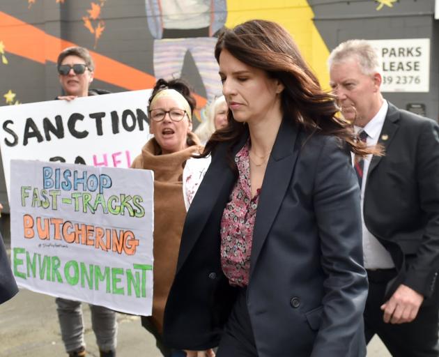 Immigration Minister Erica Stanford walks past protesters outside the Ministry of Education...