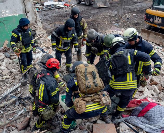Rescuers work at a Ukrainian residential building which was hit by a Russian drone strike in the...