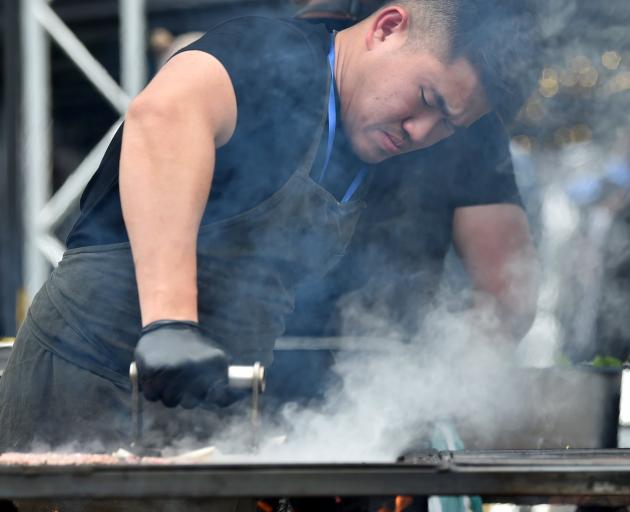 Ade Saputra, of Food by Fire from Christchurch, makes burgers for patrons at the festival.