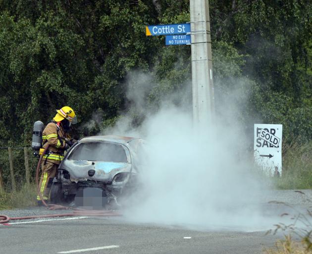 Firefighters work to extinguish the car fire. Photo: Gregor Richardson