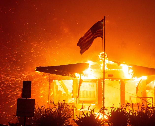 Fire engulfs a structure while the Palisades blaze burns during a windstorm on the west side of...