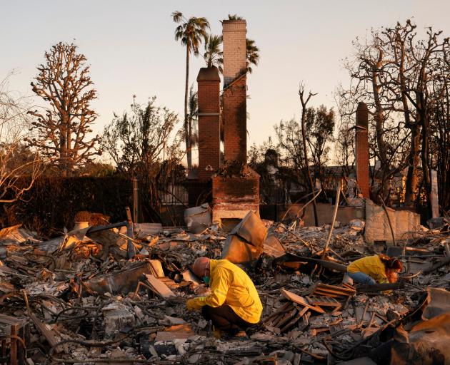 A couple look through the remains of their home, which was destroyed by the Palisades Fire, in...