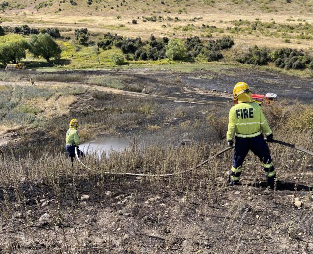 Central Otago firefighters check for hot spots after a vegetation fire was safely put out near...