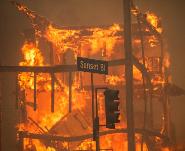 Flames from the Palisades Fire burn a building on Sunset Boulevard in the Pacific Palisades...