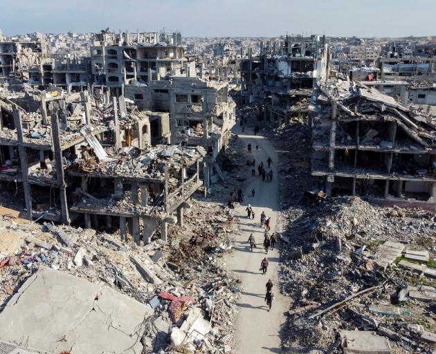 Palestinians walk past the rubble of houses and buildings in Jabalia, in the northern Gaza Strip,...
