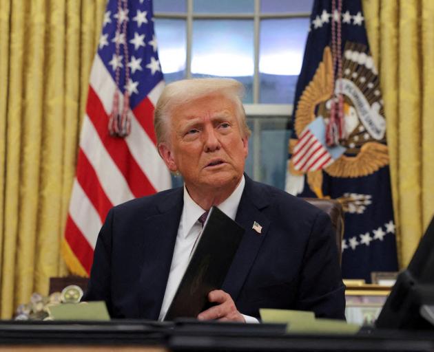 US President Donald Trump signs documents as he issues executive orders and pardons at the White...