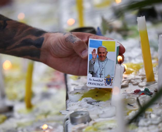 A man places an image of the late Pope Francis in a memorial outside the Buenos Aires’...