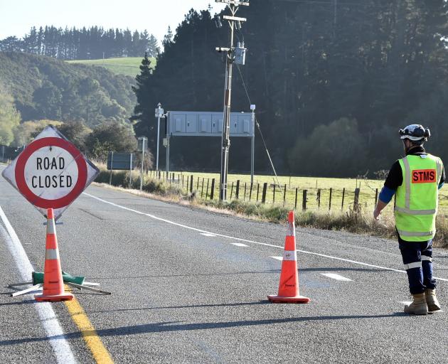 A traffic management worker redirects traffic from State Highway 1 up Donalds Hill Rd after the...