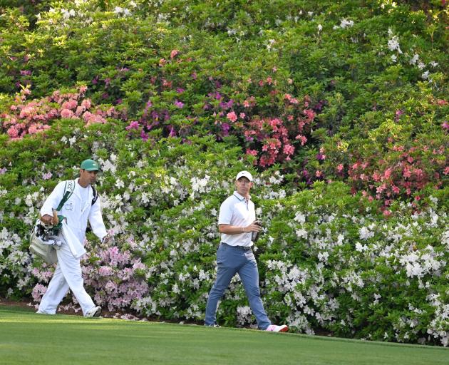 Rory McIlroy and his caddie walk among the famed azaleas at Augusta National during the third...