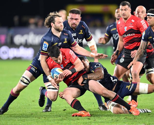 Will Jordan of the Crusaders is tackled by Oliver Haig and Jona Nareki of the Highlanders in...