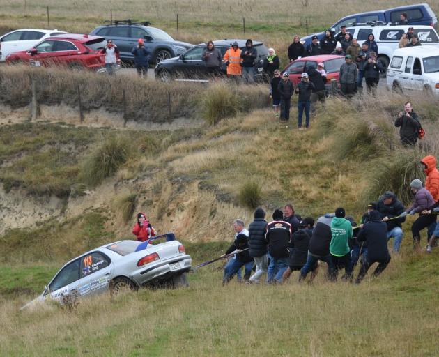 Spectators help haul the rally car back on to the road. PHOTO: DAVID THOMSON