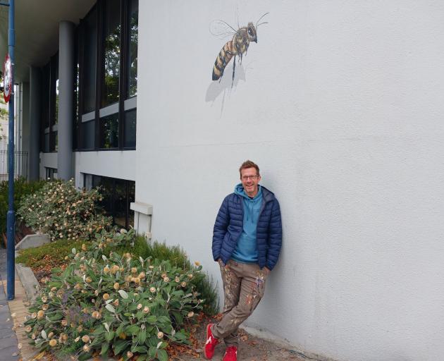 Artist Matt Willey takes a break after spending several hours painting a scout bee on the wall of...