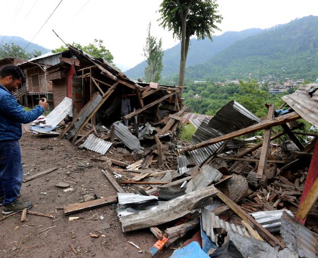 A man uses his mobile phone to film debris of shops damaged by cross-border shelling in Lagama...
