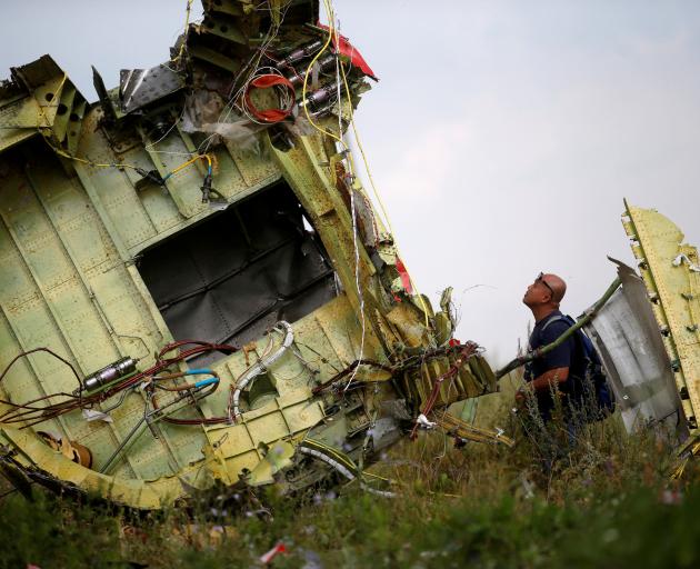 A Malaysian investigator inspects the crash site of Malaysia Airlines Flight MH17 in Ukraine....