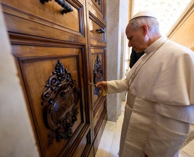 Pope Leo unlocks the door to the Apostolic Palace after it was unsealed at the Vatican on May 11....