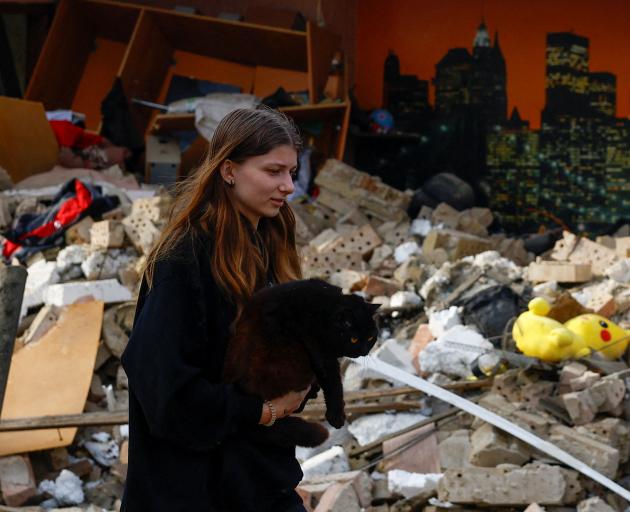 A woman walks with her cat amid the rubble from a Russian drone strike outside Kyiv. Photo: Reuters 