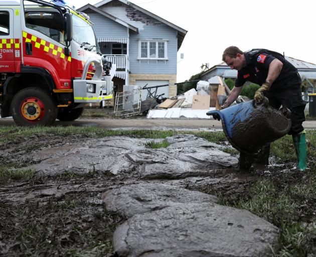 A member of the Fire and Rescue New South Wales empties mud removed from a flooded property in...