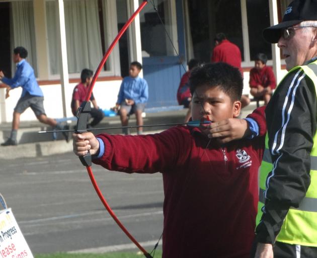 John Sausa, 11, aims his bow with the help of Ken Hedges. PHOTOS: NIC DUFF
