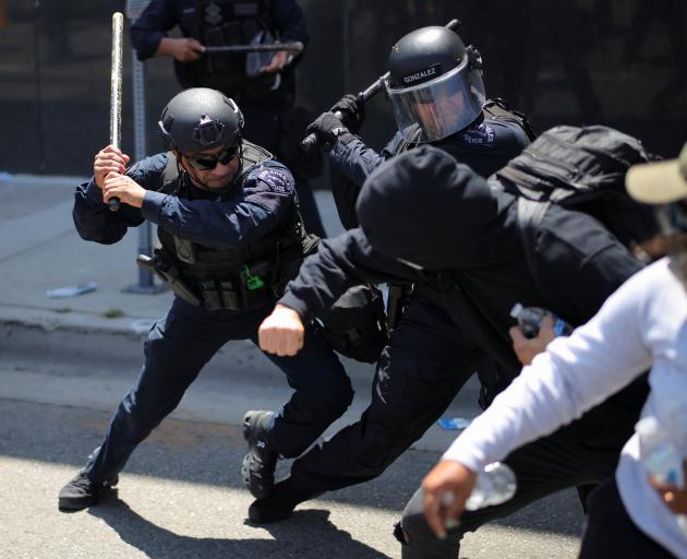Members of the Los Angeles Metro Police clash with demonstrators during a protest against federal...
