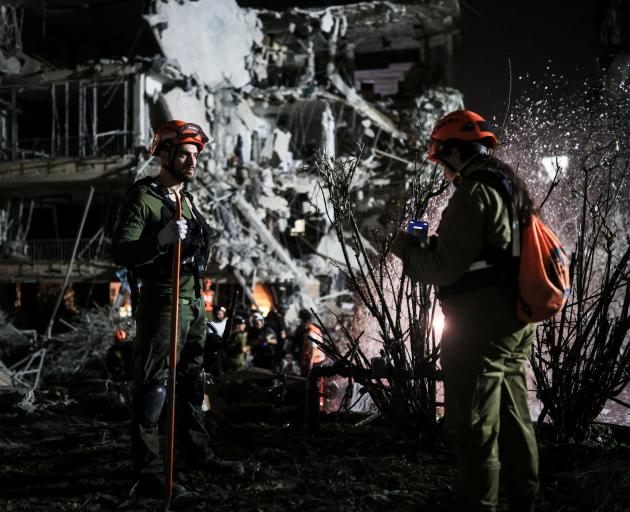 Rescue and security personnel work at an impact site following missile attack from Iran on Israel...