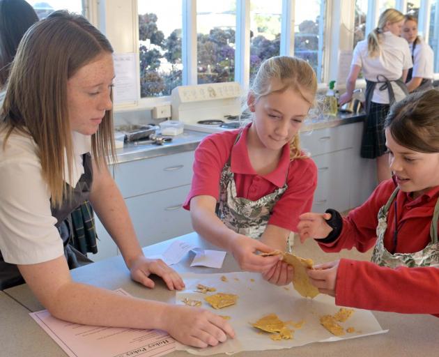 East Otago High School student Arabella Hagan (left) helps Palmerston School pupils Ivy Higgins...