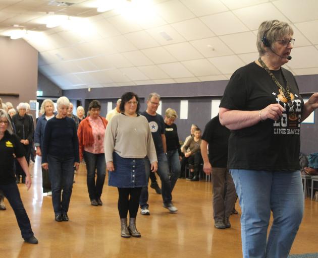 Diane Perkins teaches a group of Tussock Country festival-goers how to line dance at the Town &...