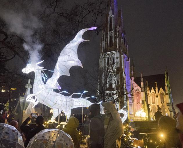 A glowing dragon exhales a smoke cloud over visitors eagerly waiting to be let into the Dunedin...