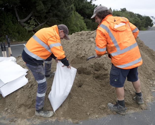 Delta employees Peter Soper (left) and Simon Smaill fill a sandbag at the Dunedin Ice Stadium...