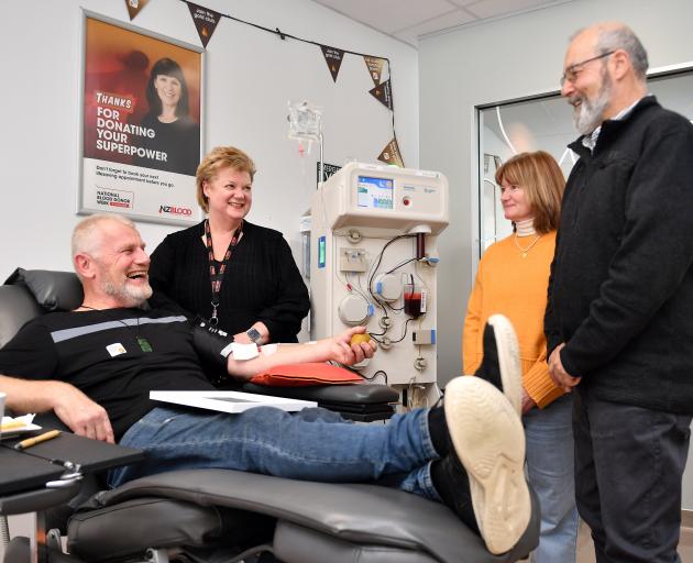 Cancer patient Adrian Hood looks on as Terry Taylor makes his 50th plasma donation. Also enjoying...