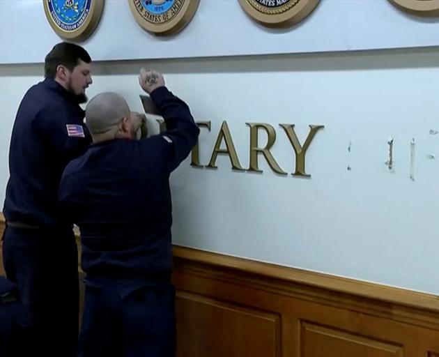 Workers remove signage for the Secretary of Defense after Trump's order to rename the department....