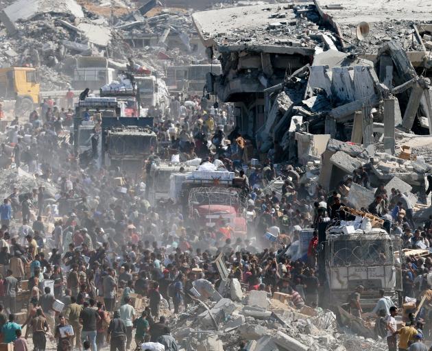 Palestinians collect aid supplies from trucks that entered Gaza, amid a ceasefire between Israel...