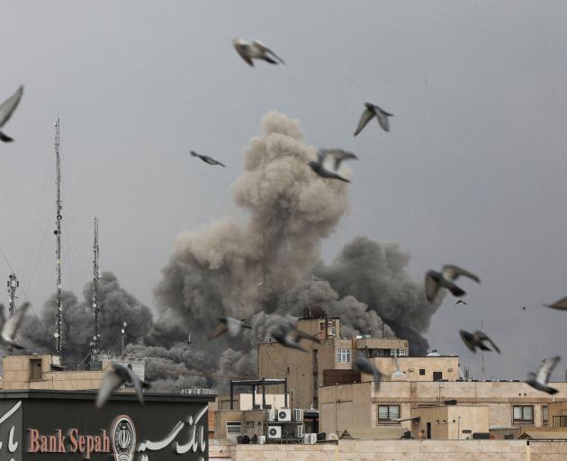 Birds fly as smoke rises following an explosion, after Israel and the US launched strikes on Iran...