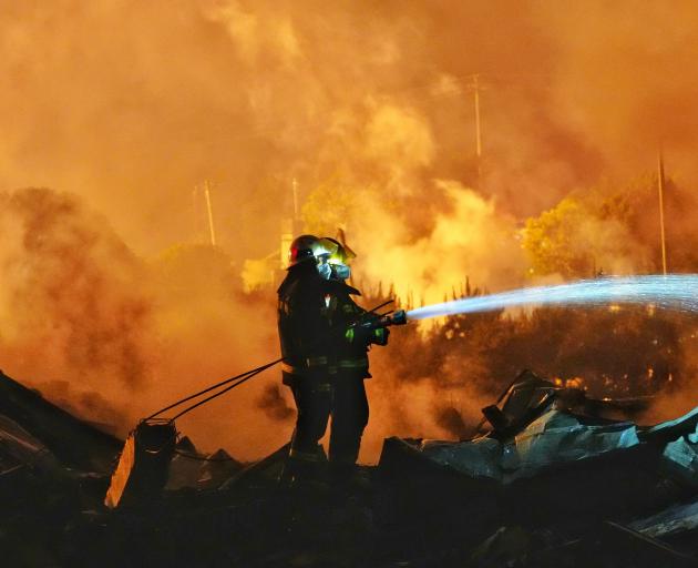 Firefighters work to distinguish a fire following a blast at a fireworks manufacturing factory in...