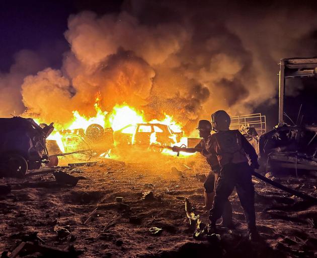 Civil defence workers attempt to extinguish a fire following an Israeli strike on a warehouse in...