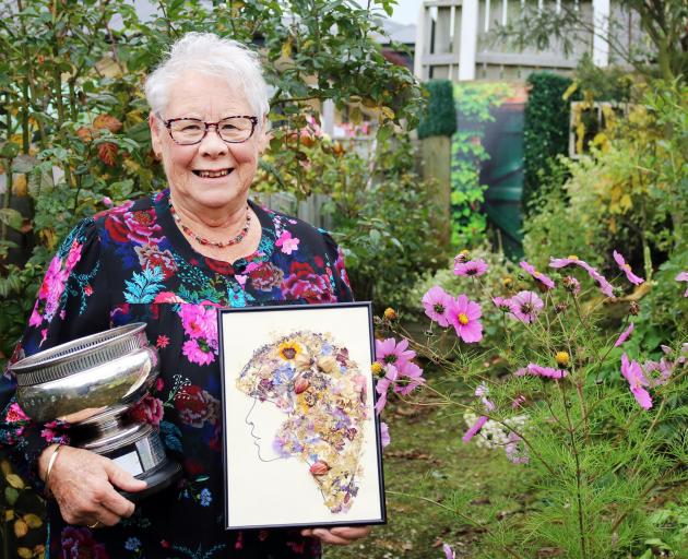 North Otago Floral Art Society member Barbara Watt in her garden with her trophy and artwork May...