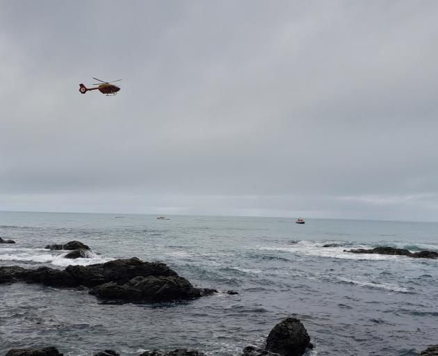 Two boats and a helicopter search close to the overturned vessel. Photo: Sean McCabe